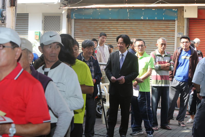 Der Wartende im Anzug ist Premierminister William Lai vor einem Wahllokal in Tainan